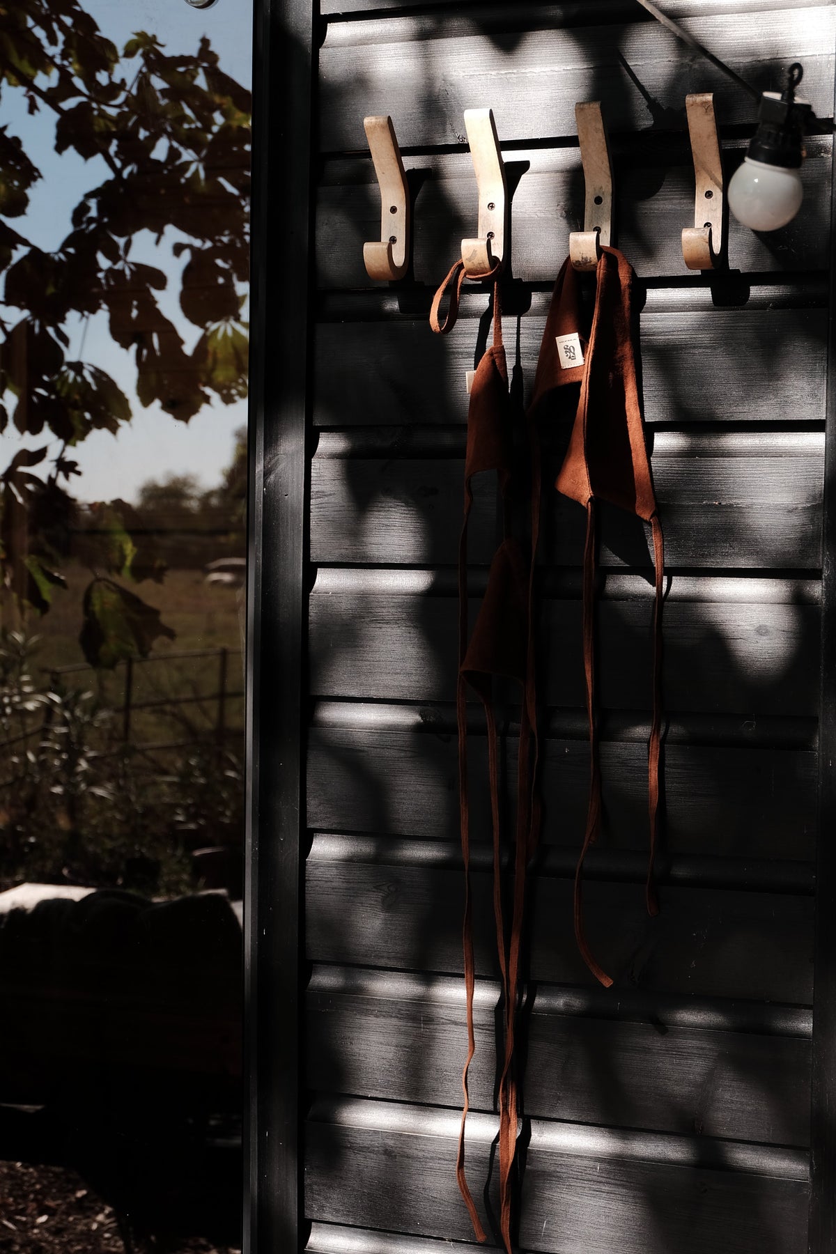 brown bikini hanging on a black wood-cladded sauna with reflection of trees