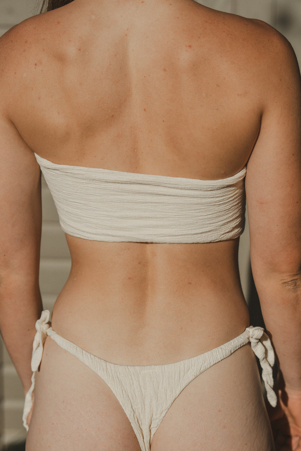 Person wearing a beige bikini set with a blurred background